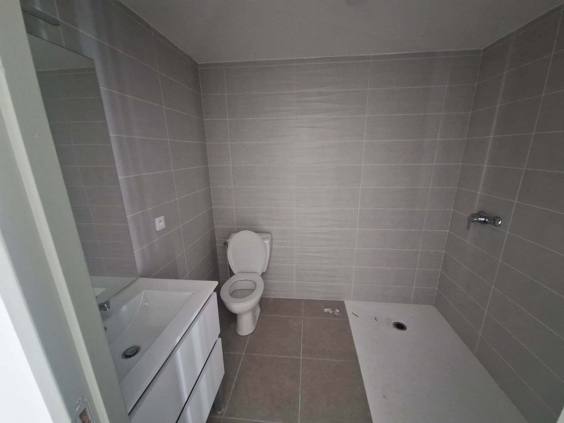Salle d’eau carrelée avec douche.
