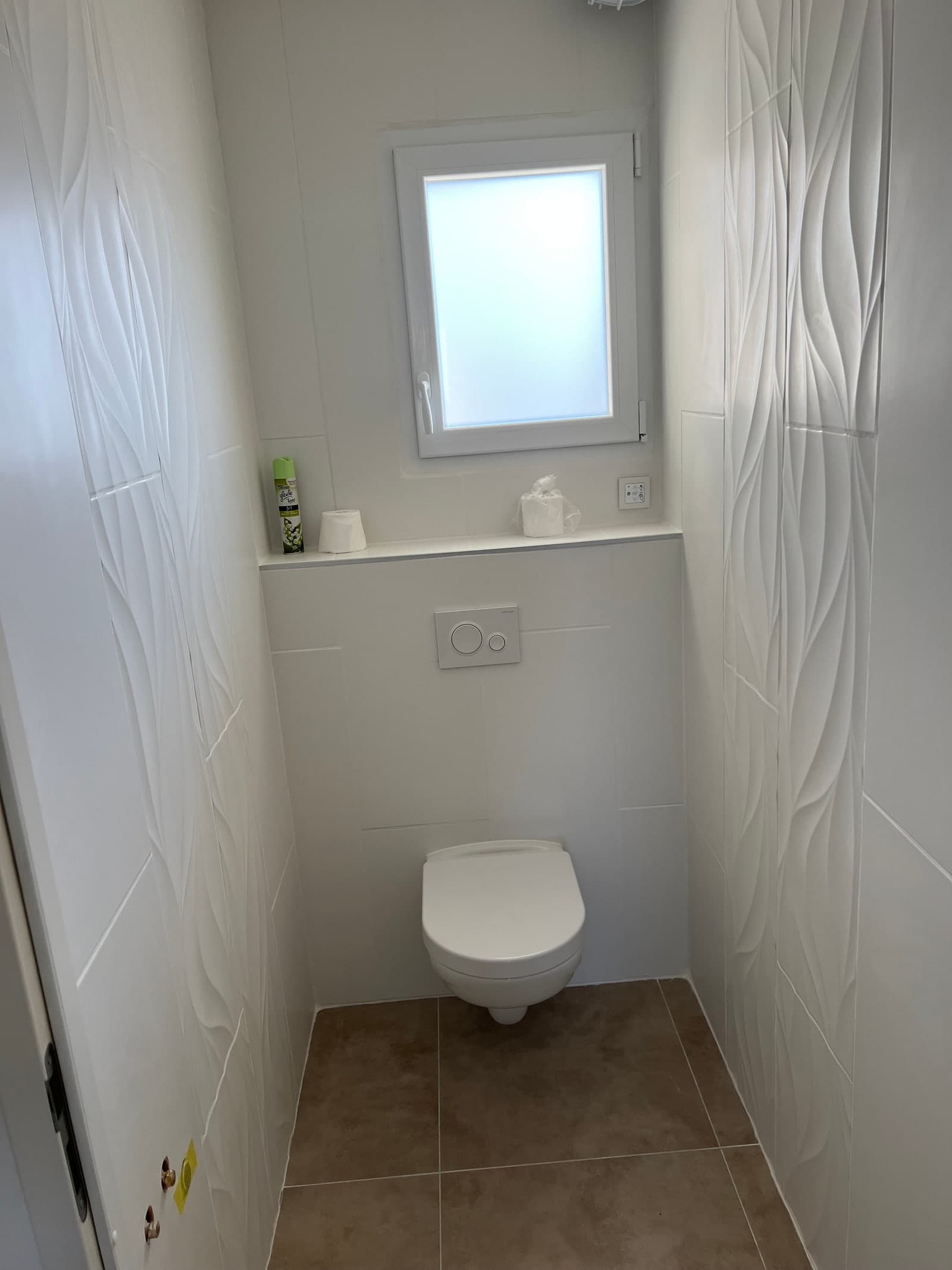 WC suspendu, faïence murale blanche et carrelage dans la maison à Verrières.