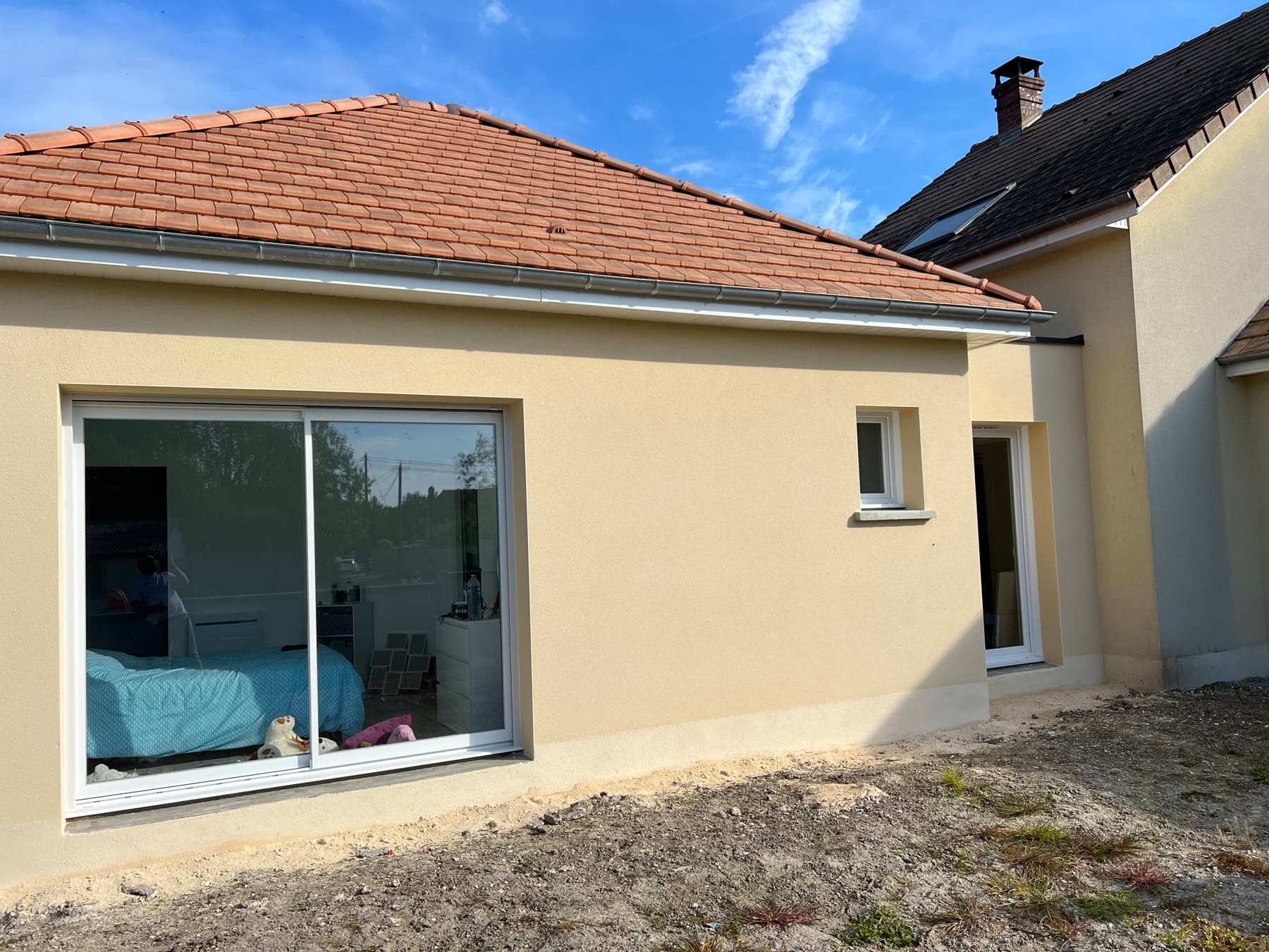Façade enduite et liaison visible avec la maison existante.